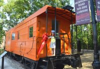 Little girl with a train conductor hat standing on the back platform of a caboose