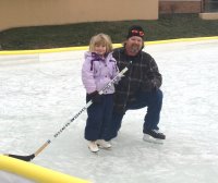 Father and daughter on the ice rink with a hockey stick